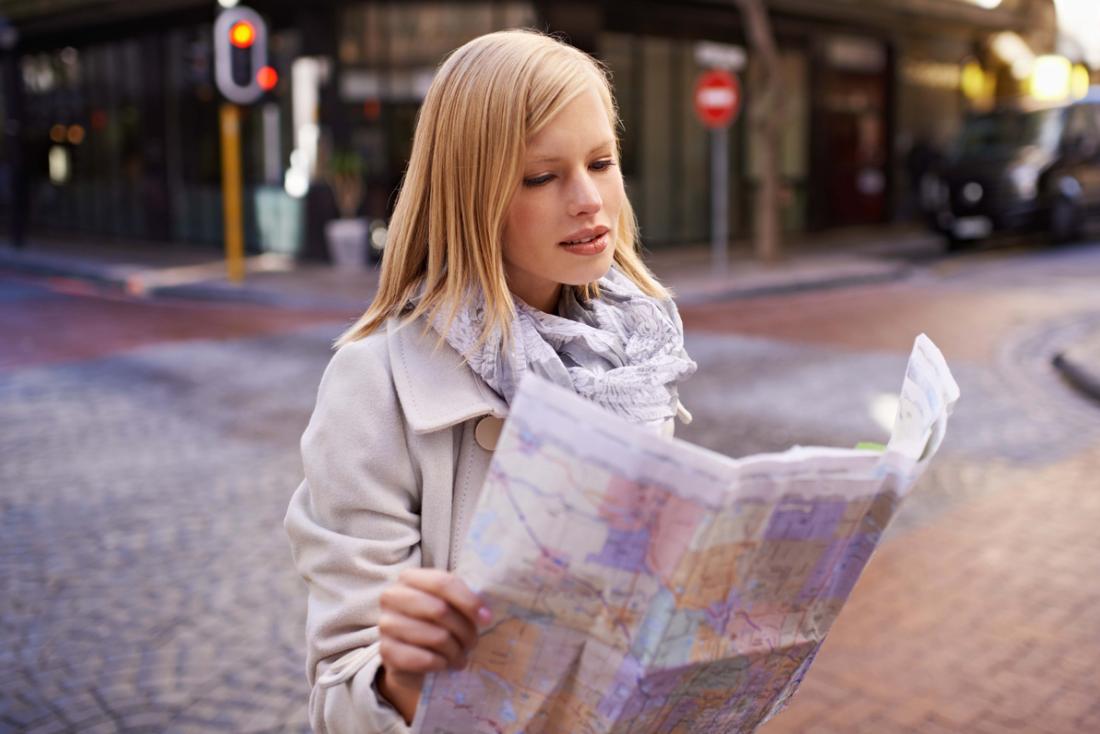 Woman trying to read map, lost in city.