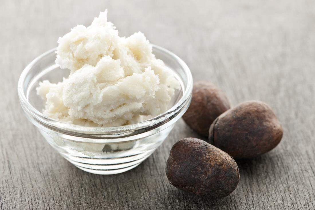 Shea butter in a bowl next to shea nuts.