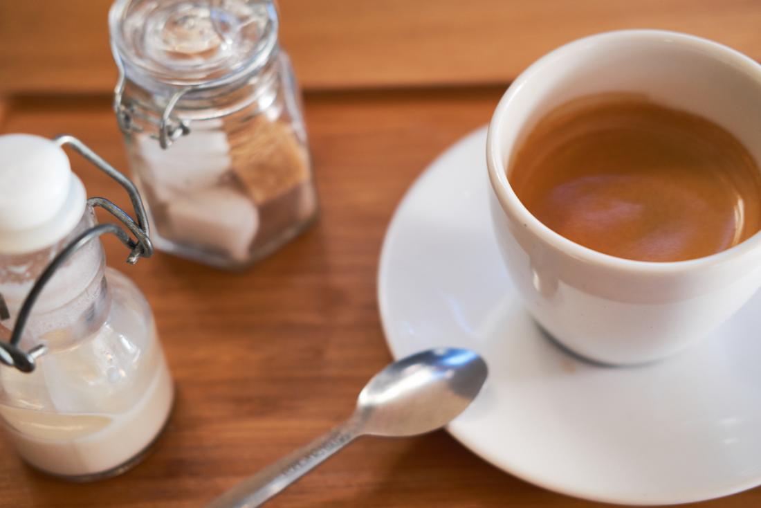 Cup of coffee with milk and sugar cubes.