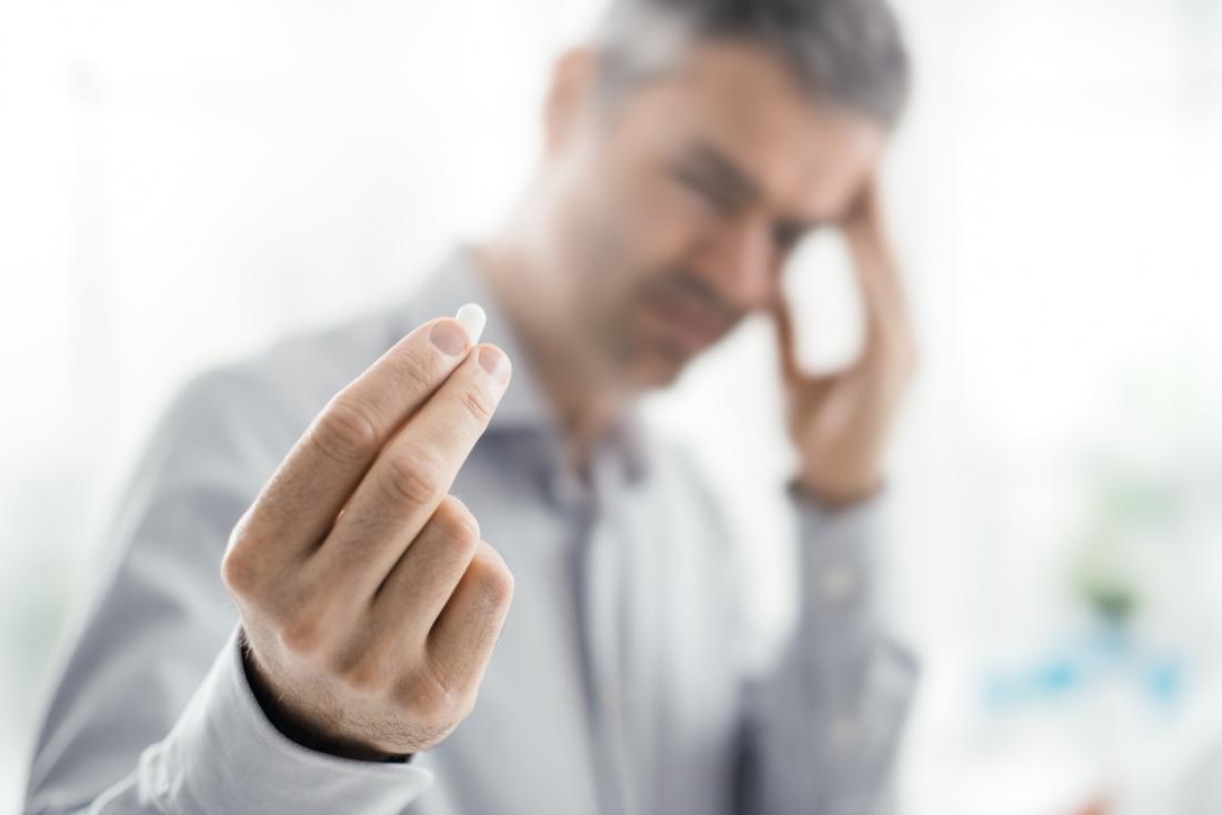 Man with a headache taking a tablet