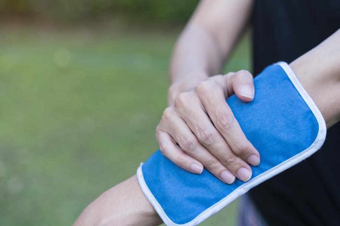 Femme appliquant une poche de chaleur ou de glace sur son coude pour soulager la douleur.