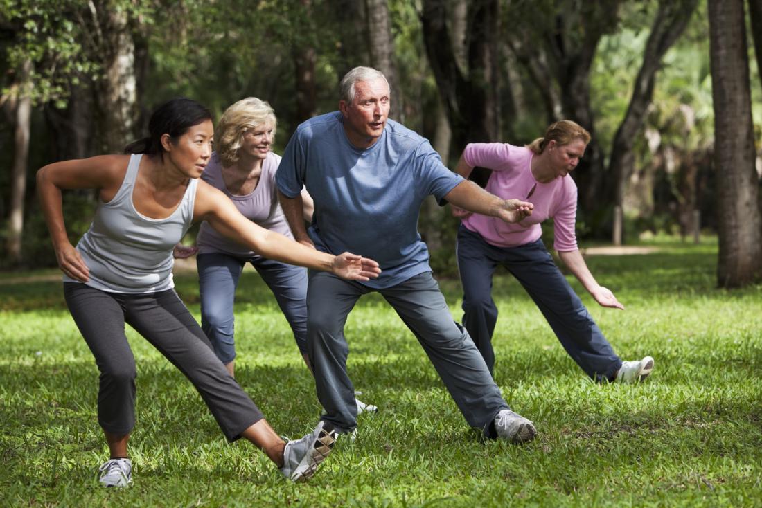 Group practicing tai chi and mindfulness in park.