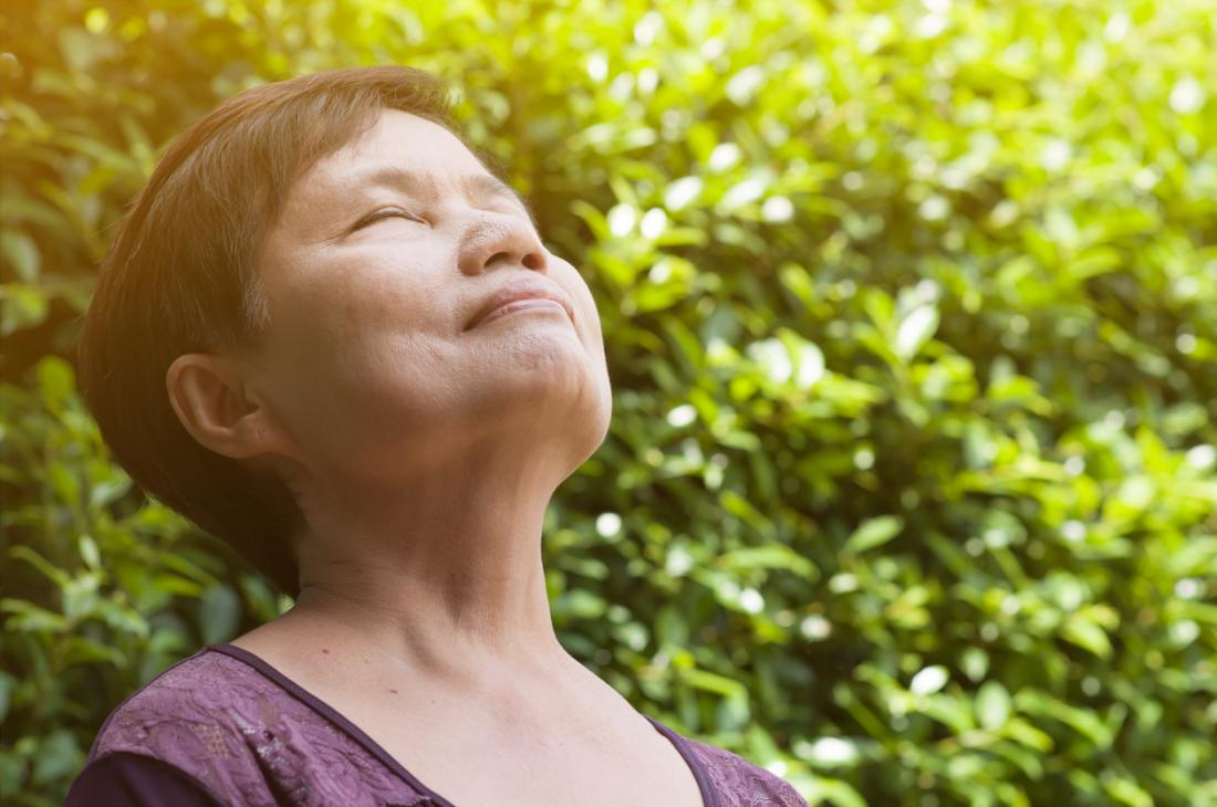 Woman taking deep breaths outside, inhaling fresh air.