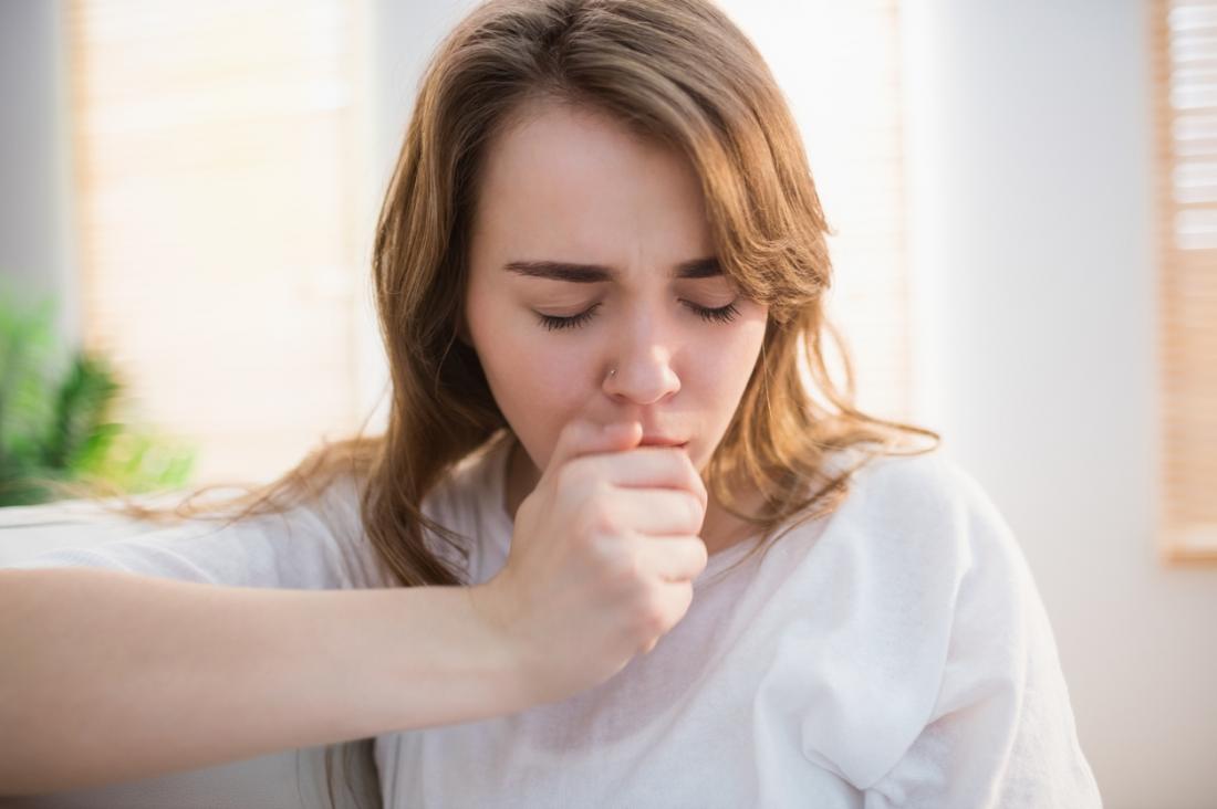 Woman coughing into hand.