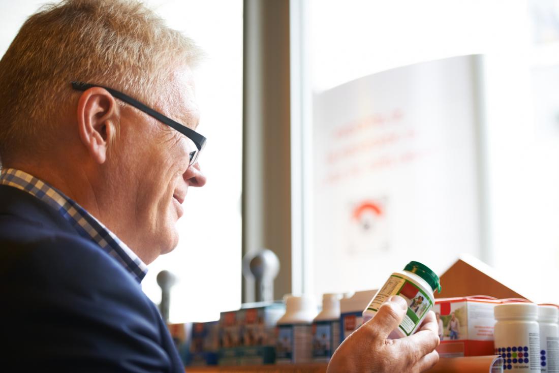Man looking at pack of supplement vitamins in shop.