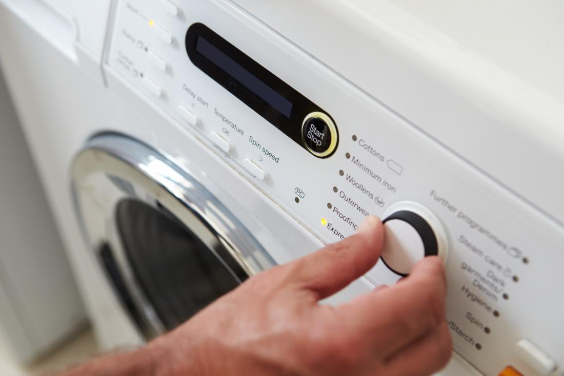 mans hand turning on washing machine