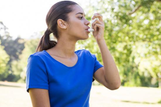 Woman with asthma using inhaler outside