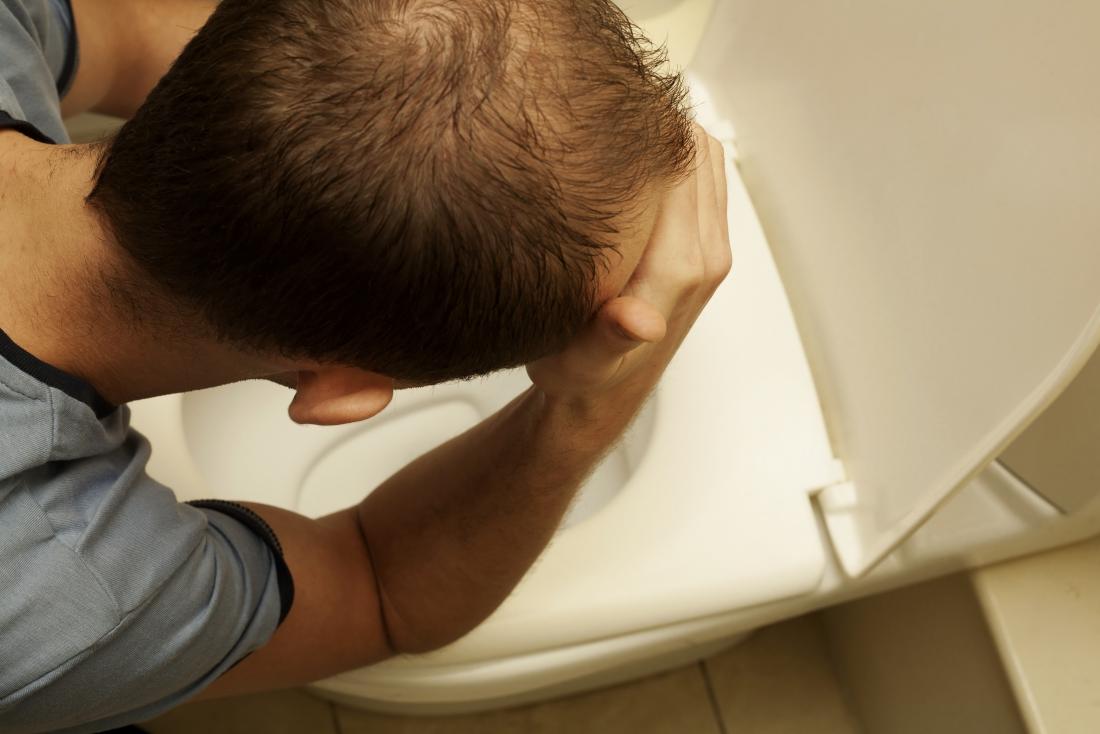 man holding head over toilet