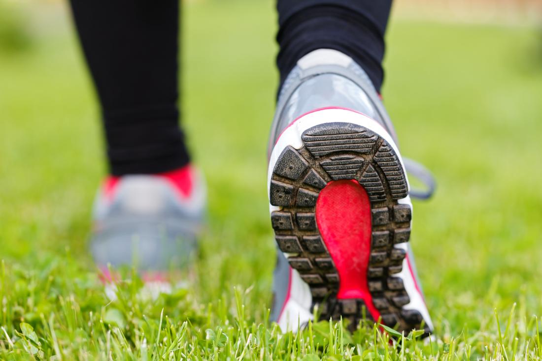Person walking in sports shoes over grass.