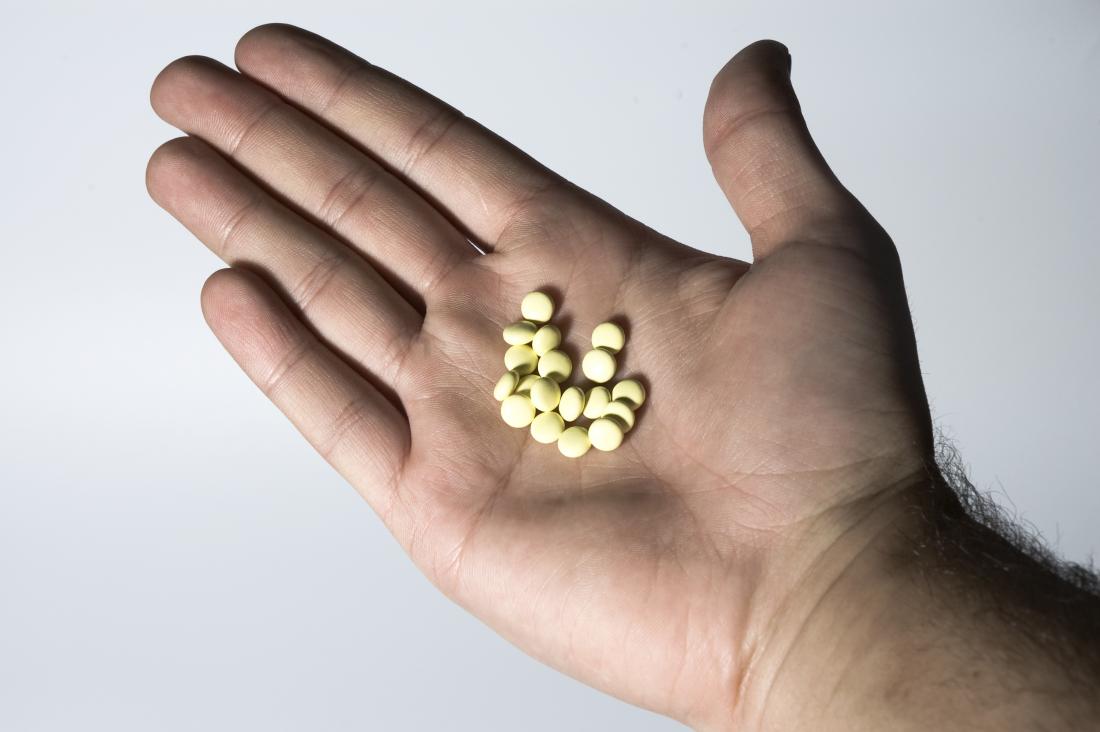 small yellow pills in mans hand