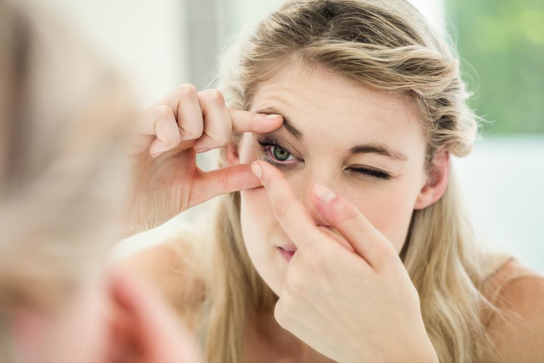young woman putting in contact lense