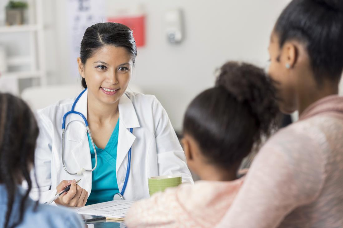 Female doctor speaking to mother with children.
