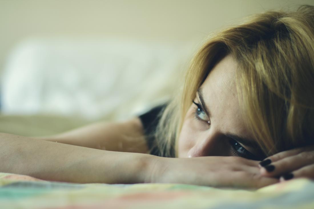 woman laying on bed looking sad