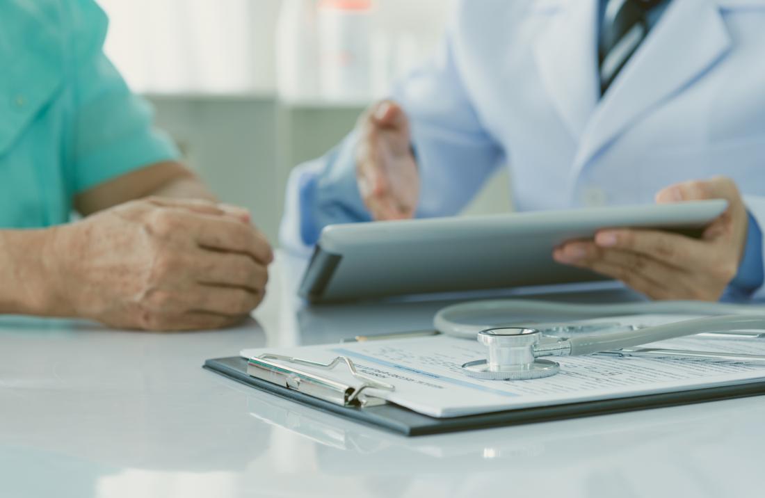 Doctor discussing results with patient, with clipboard and stethoscope in foreground.