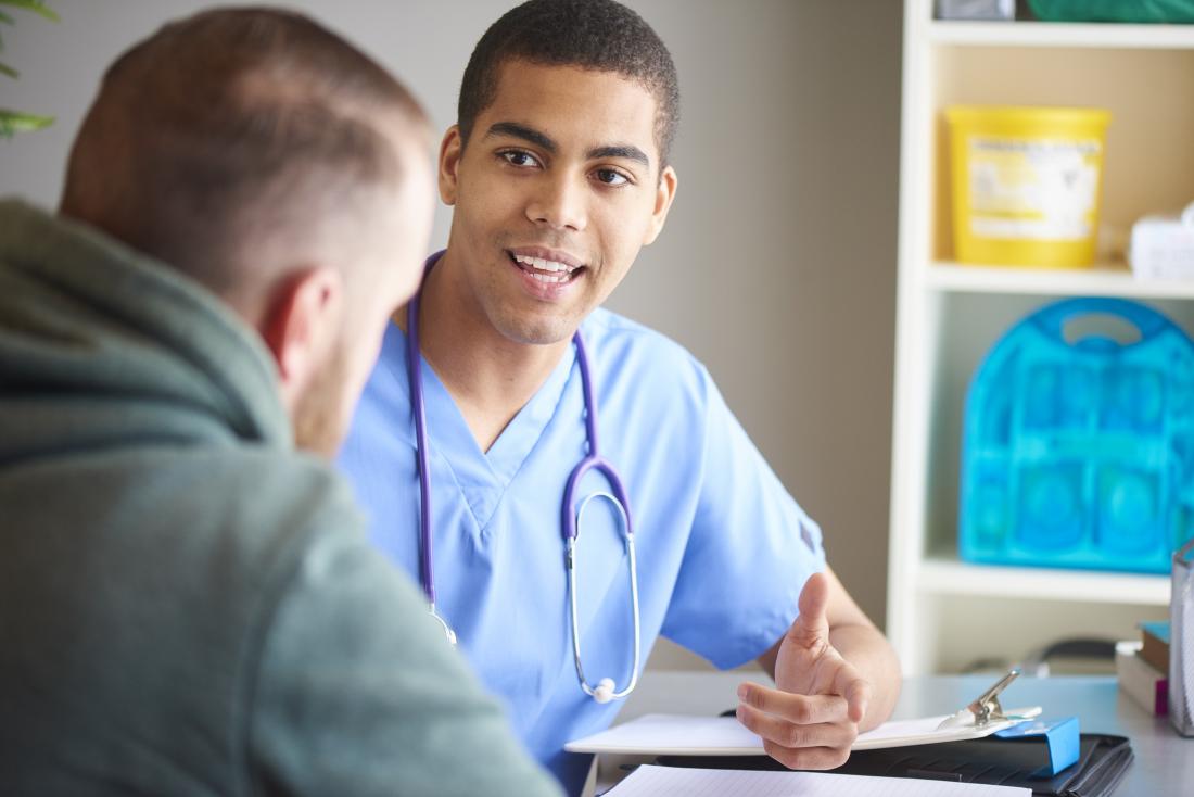Young male doctor speaking with young male patient.