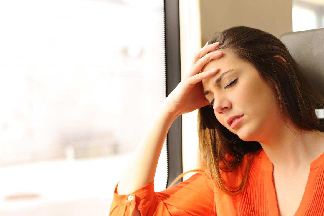 Dizzy woman on train experiencing headache and fatigue.