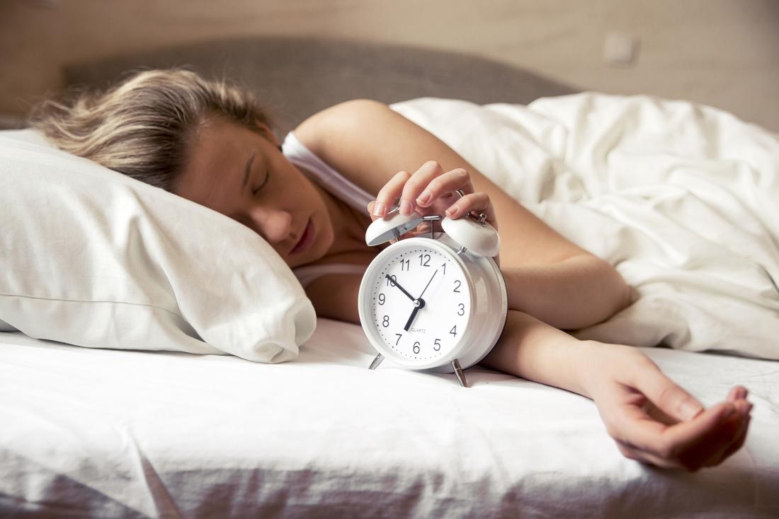 woman in bed with alarm clock