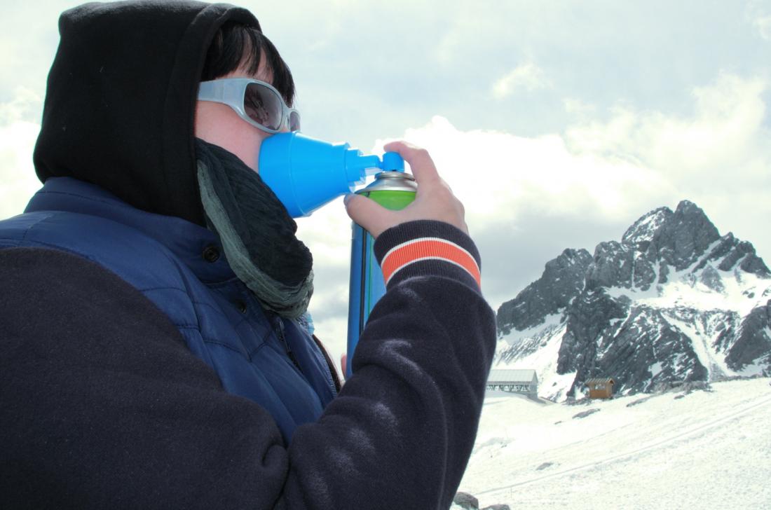 Person with altitude sickness on snowy mountain, using oxygen mask.