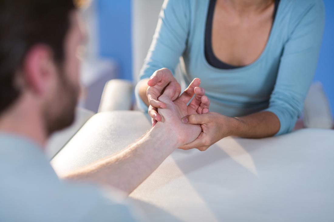 doctor inspecting patients hand, palm, and wrist.