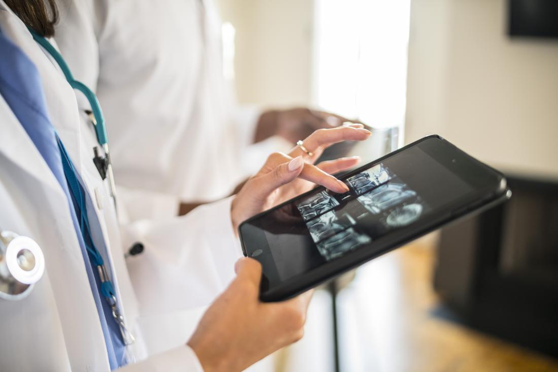 Doctor looking at CT scans on tablet.