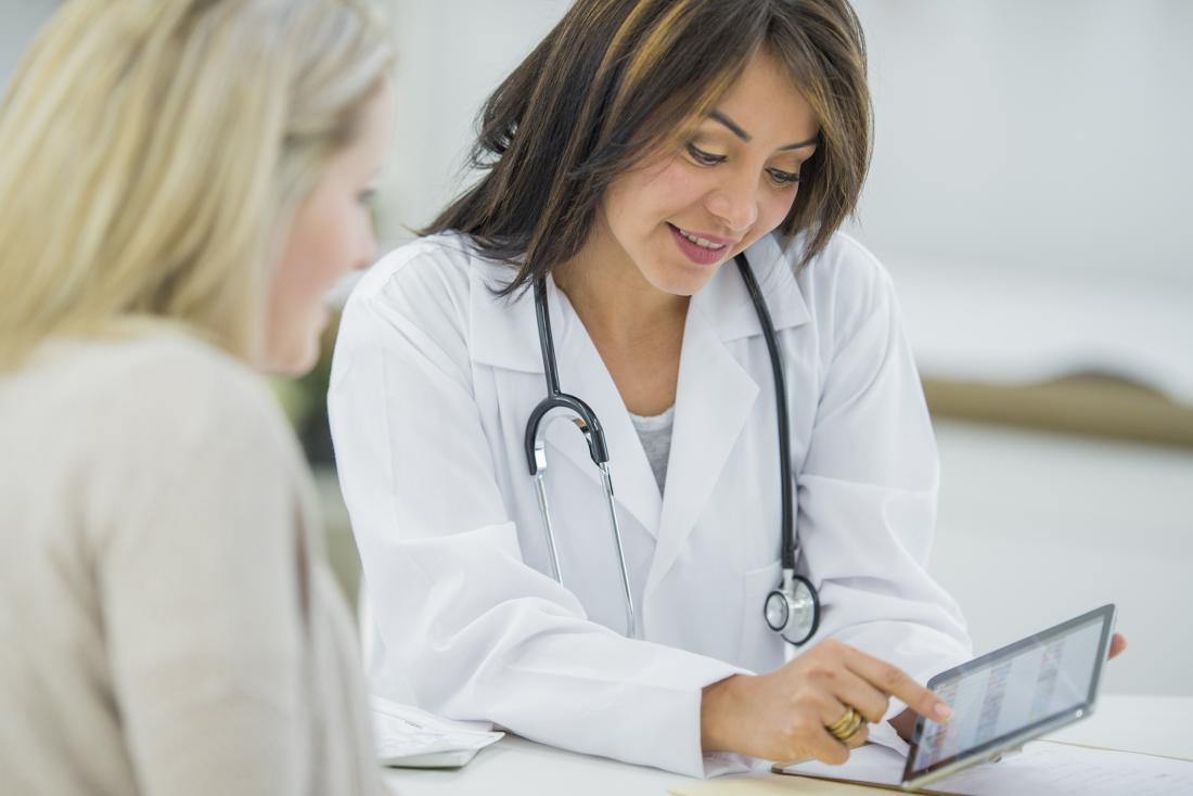 Doctor speaking to female patient about results using tablet.
