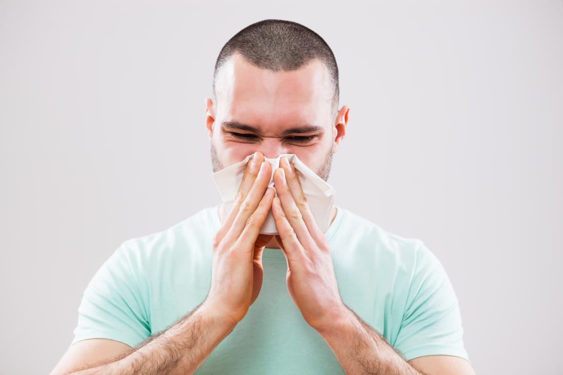 Man blowing his nose into tissue because of cold infection or sinusitis.