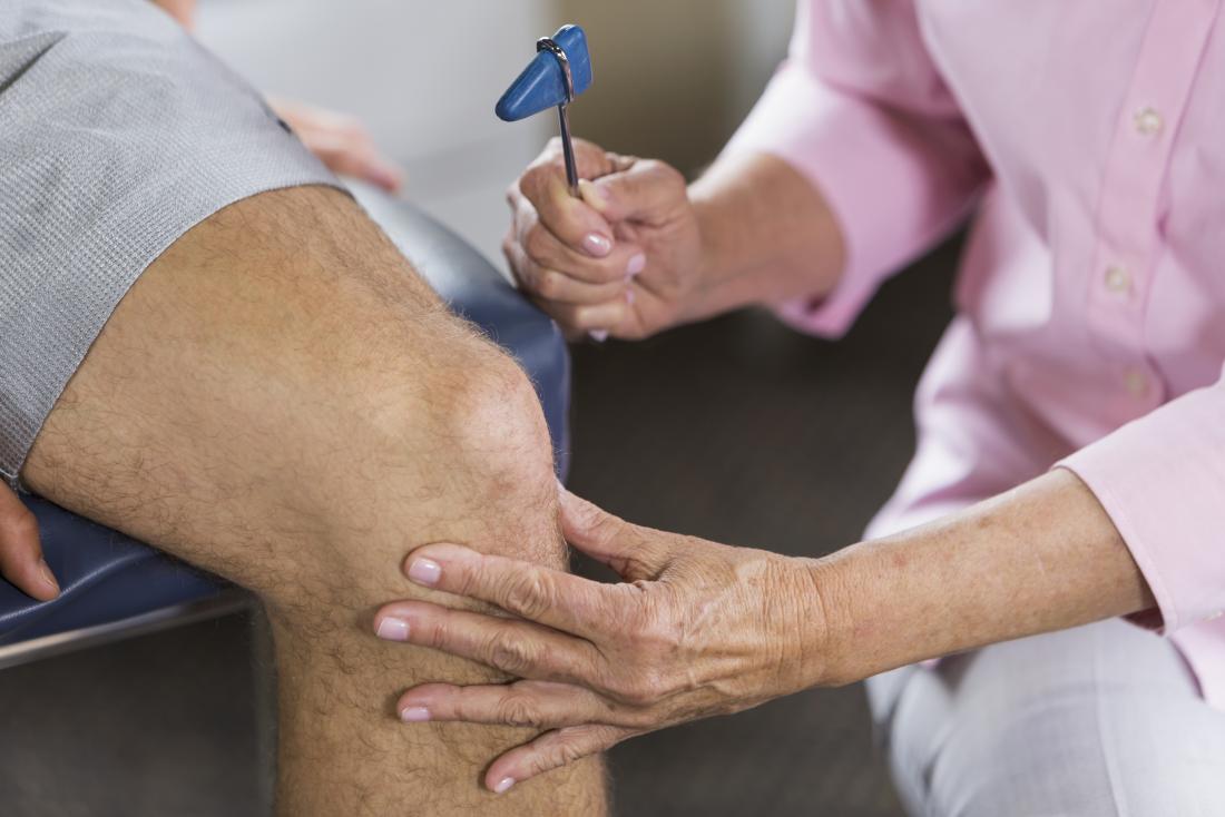 physical therapist testing patients reflexes in knee joint.
