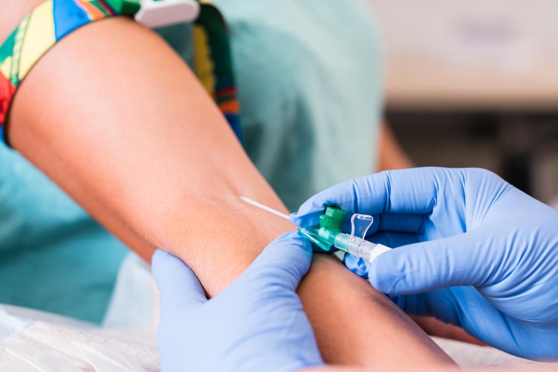 Person having blood sample taken for testing by gloved nurse.