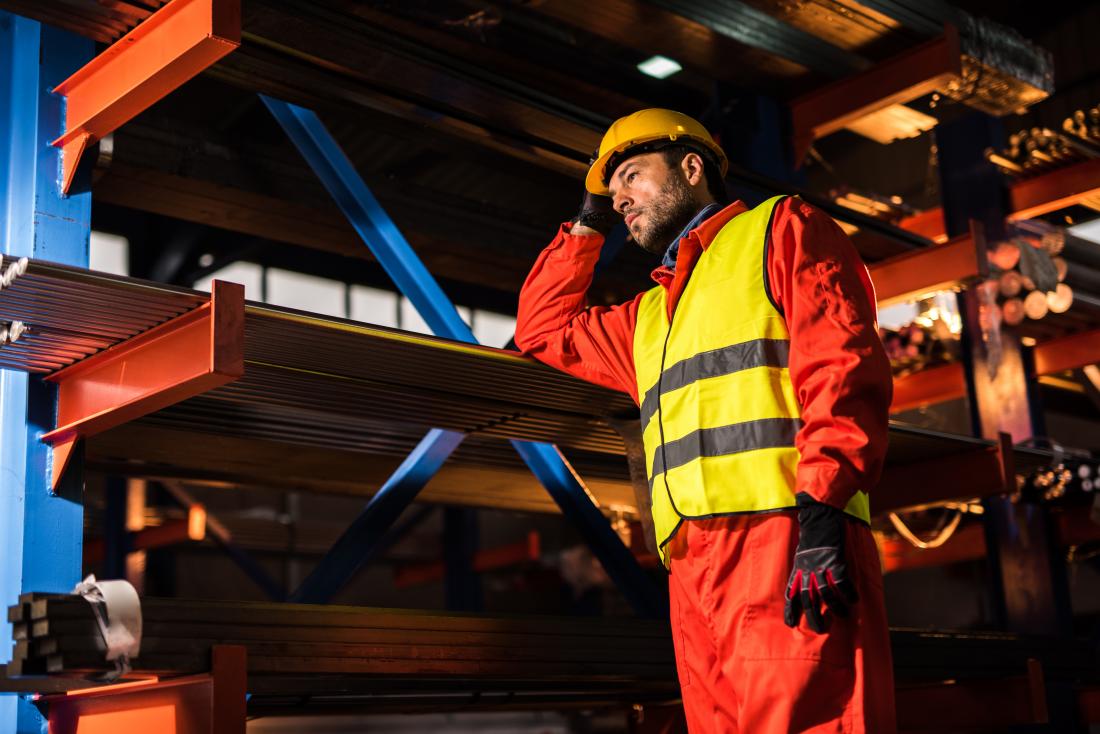 man working in industrial factory environment with protective gear and helmet.
