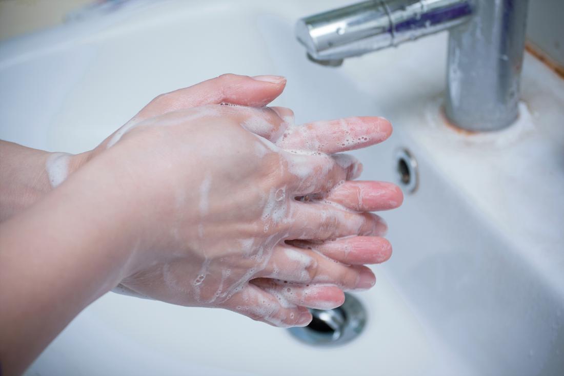 Person washing their hands under tap with soap.