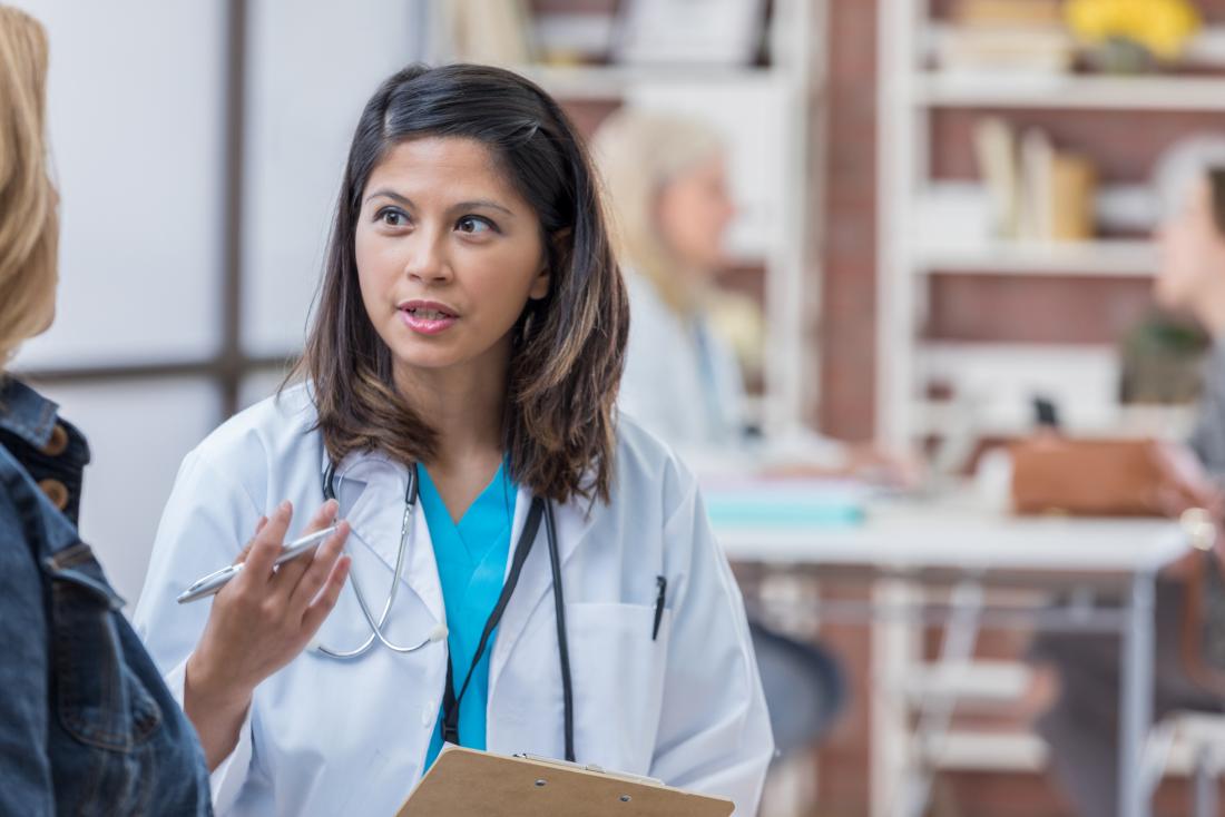 Female doctor speaking to patient in open office.