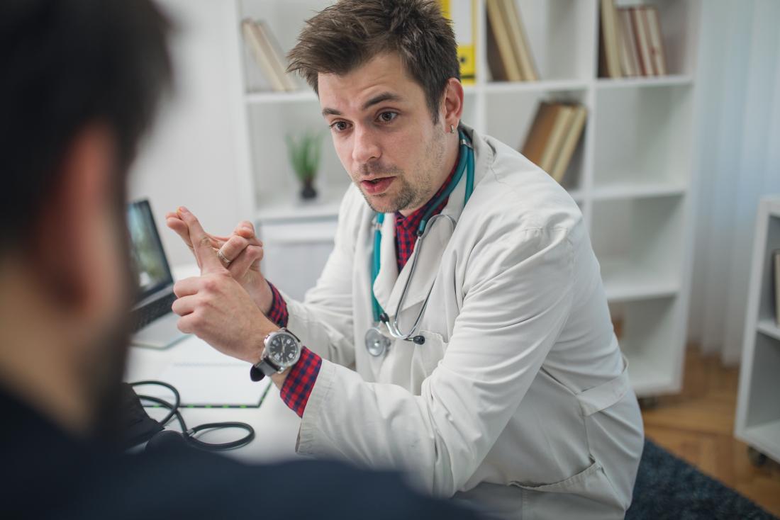 Male doctor listing causes of condition to man.