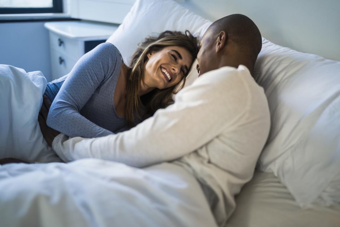Man and woman in bed, laughing.
