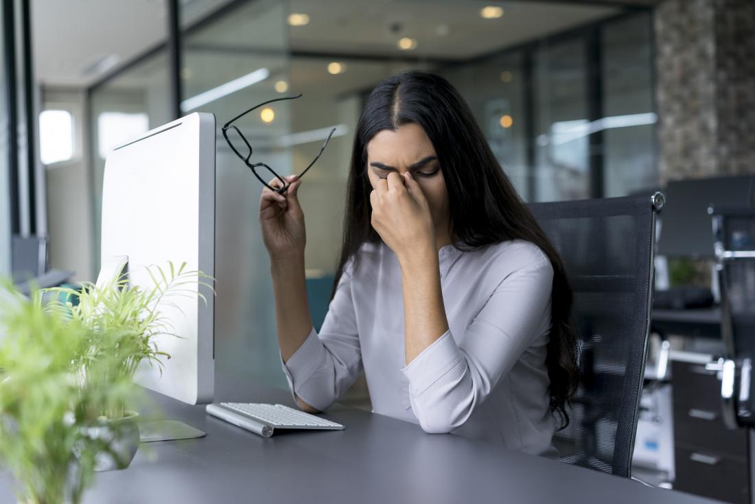 Woman with headaches stress pain at work, pinching bridge of nose.