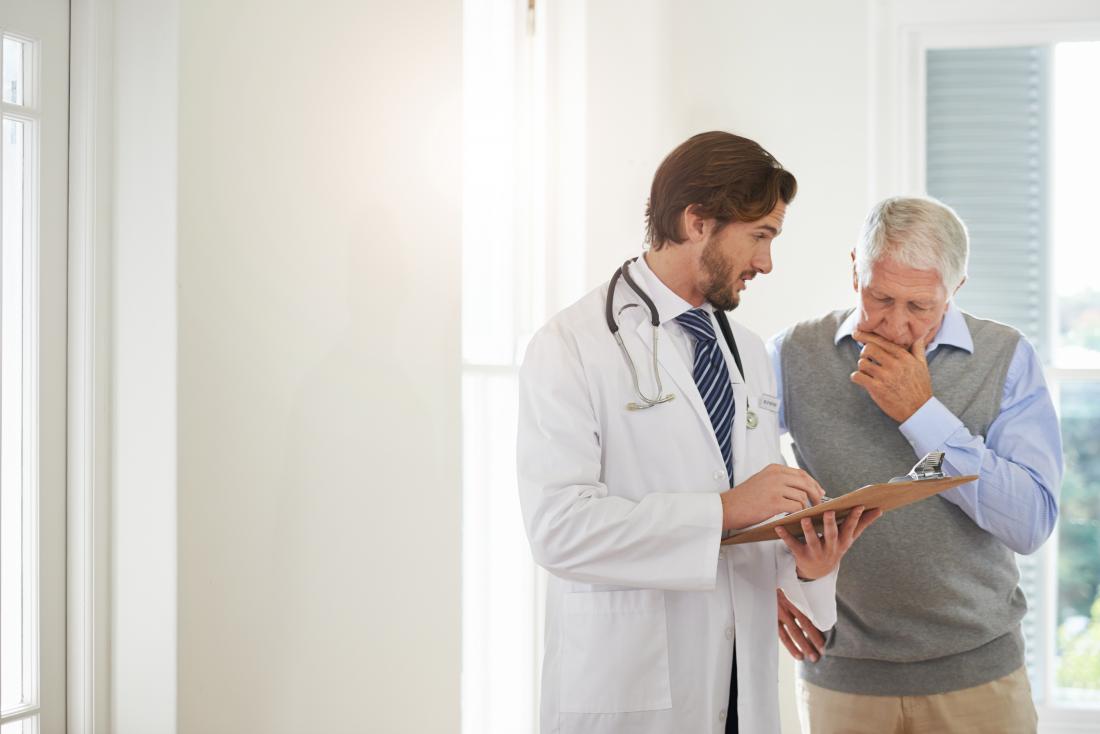 Older male patient looking at doctor's clipboard.