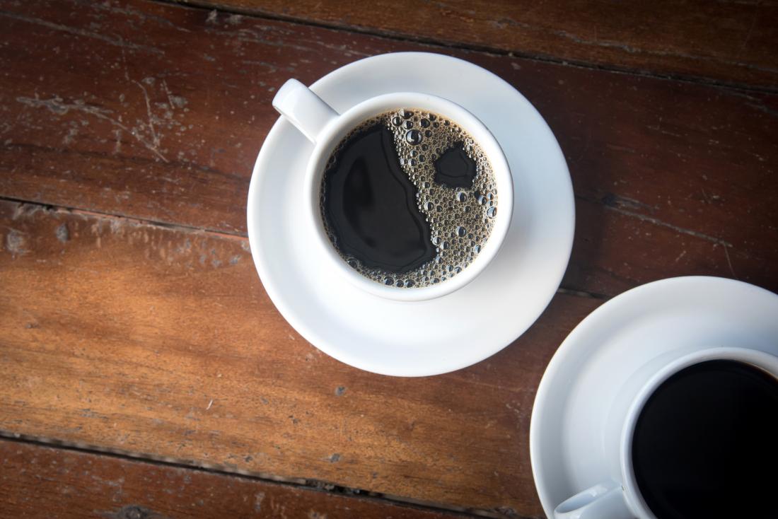 black coffee in two cups on wooden table.