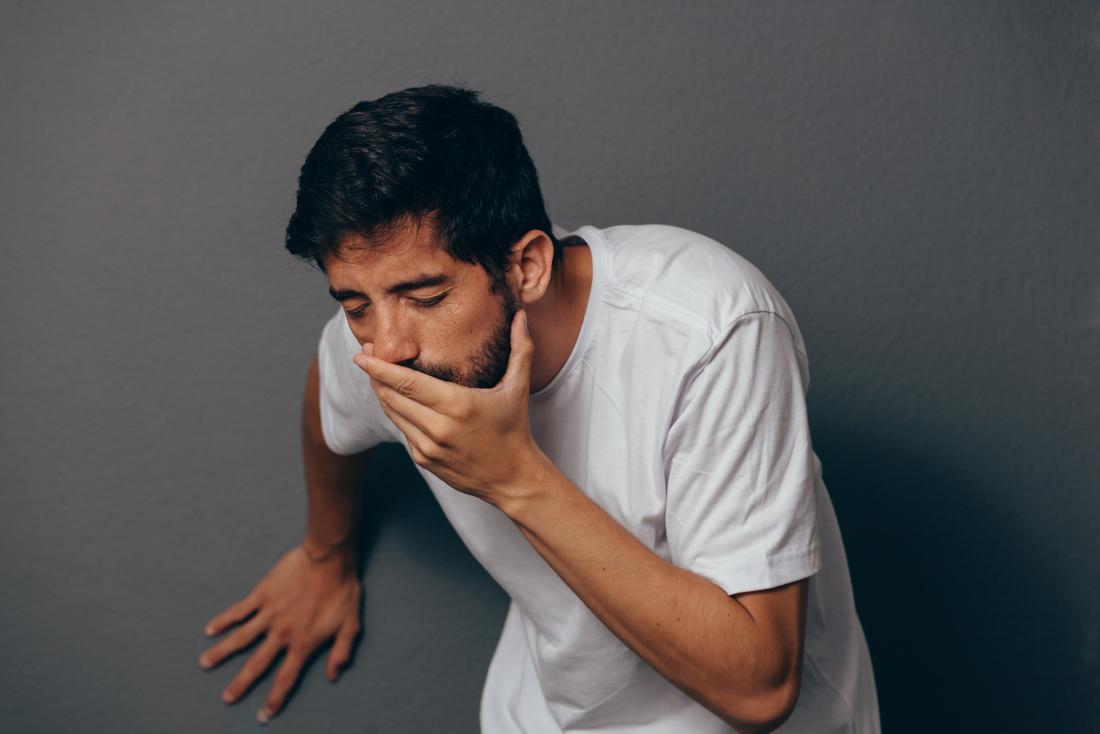 Man about to vomit green or yellow bile covering his mouth with his hand.