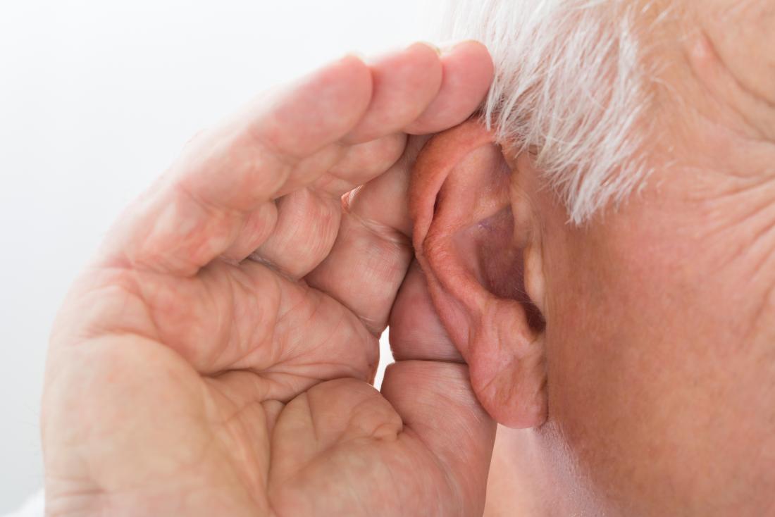 an older man with his hand by his ear
