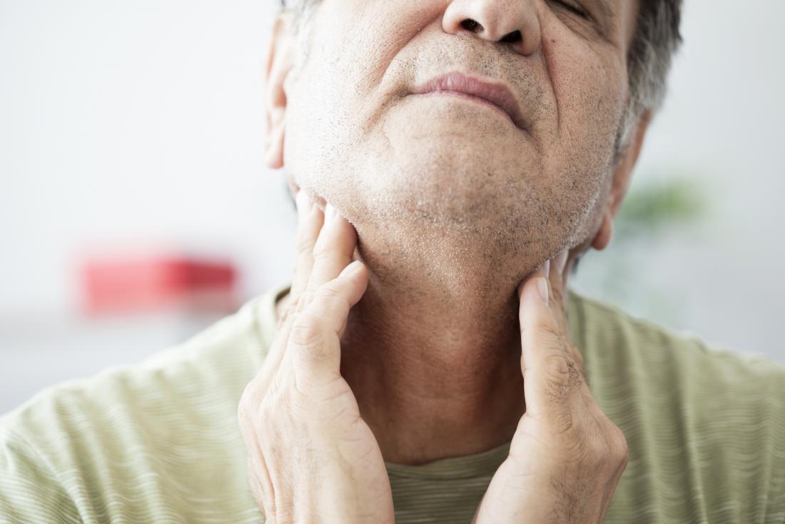 sore throat on one side in man holding sides of neck