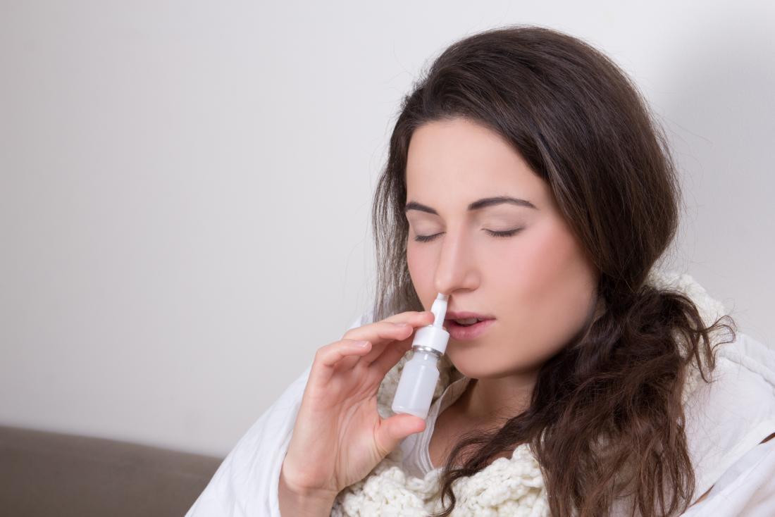 Woman using nasal spray decongestant.