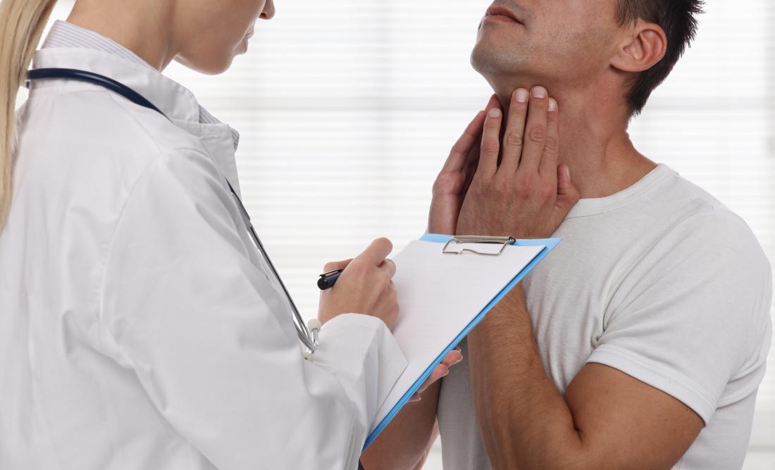 Male patient explaining problem with throat and neck to female doctor with clipboard.