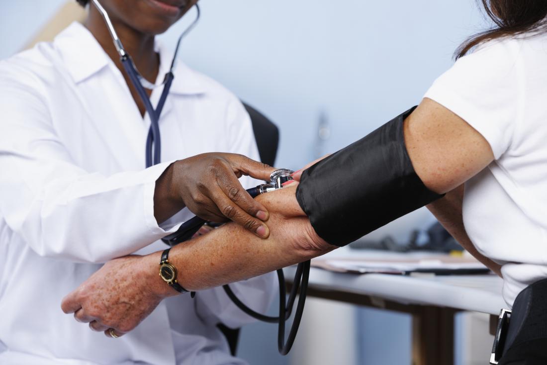 doctor taking female patients blood pressure