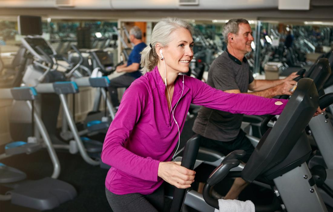 Older woman in gym exercising on machine.