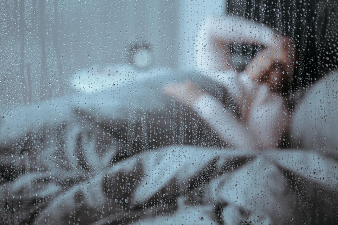 Lady in bed looking out of window wondering why she always feels sick 