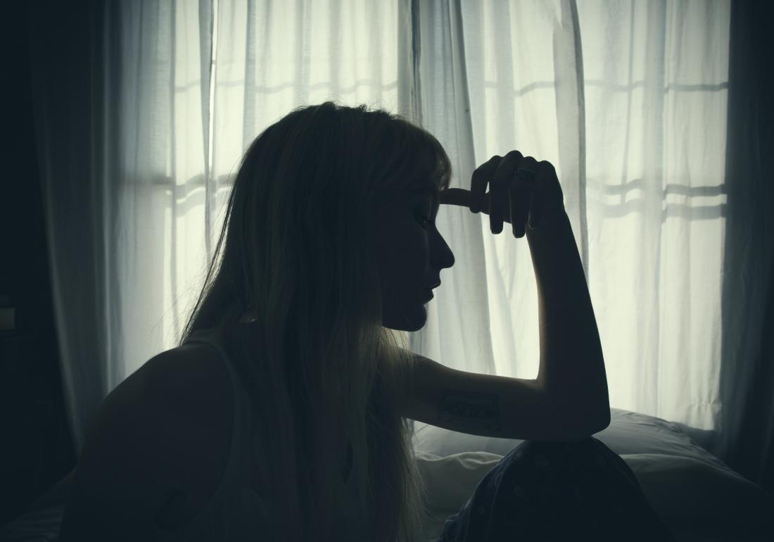 a sad woman sitting by the window
