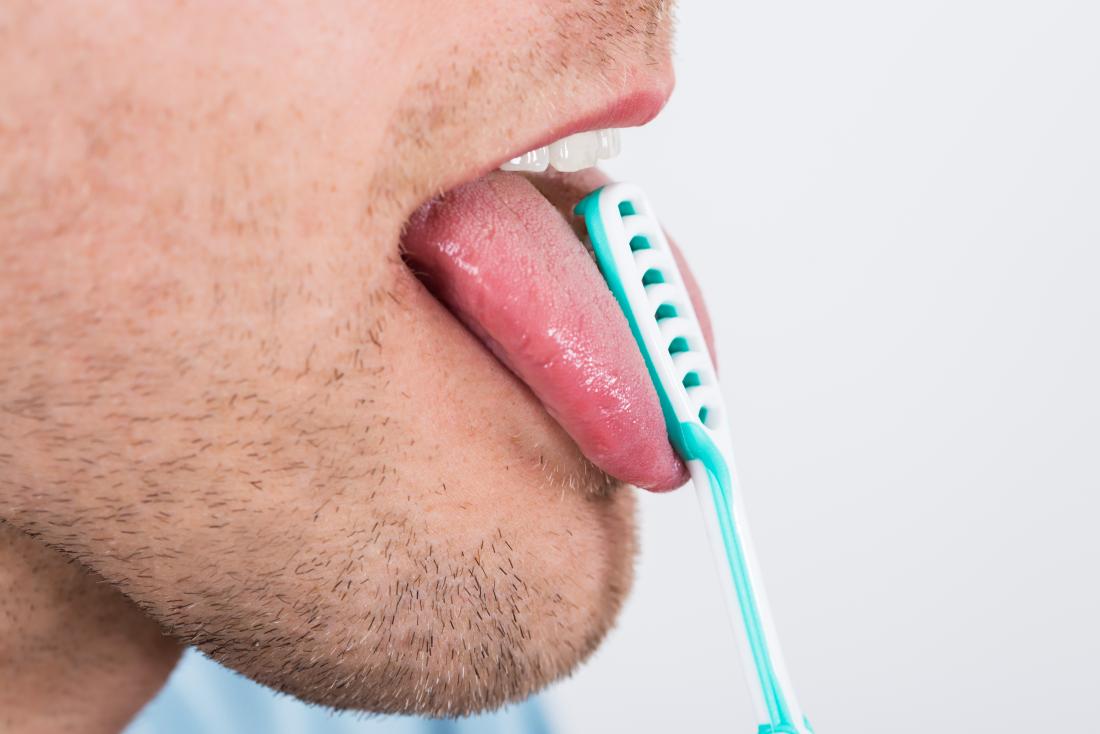 man using a tongue scraper