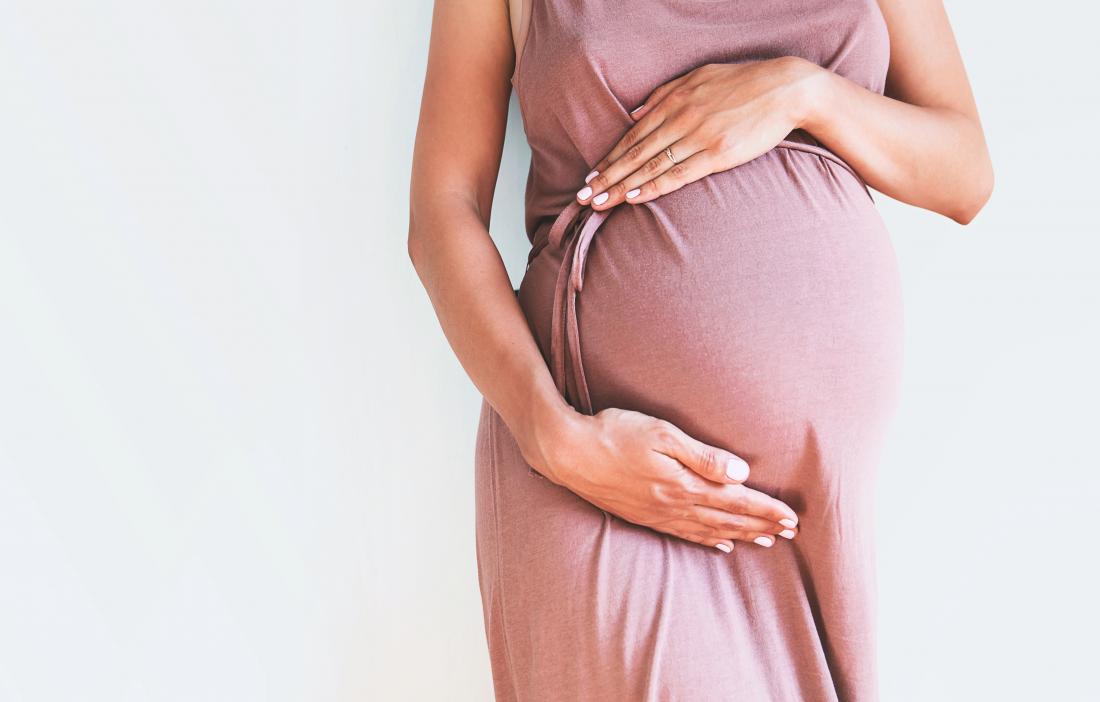 Pregnant woman holding baby bump.