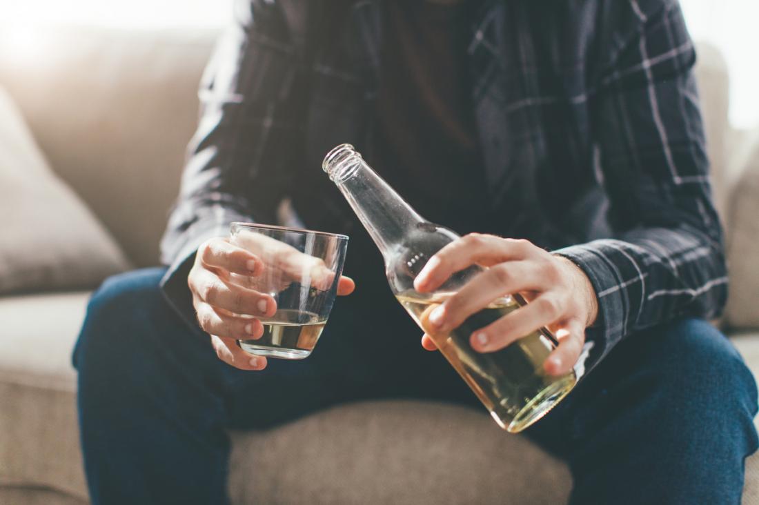 man sitting down pouring alcohol into glass