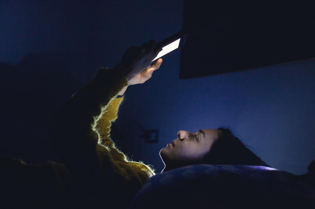 person looking at bright phone screen at night