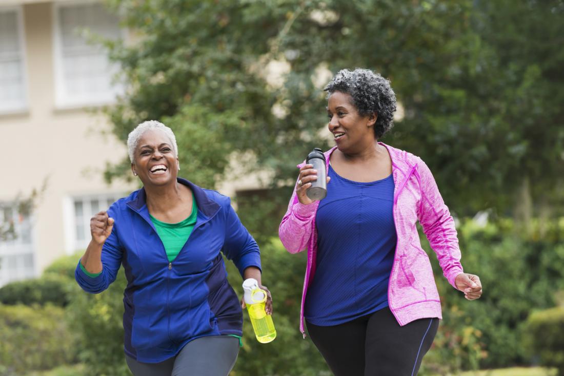 two older women having a laugh while exercising outdoors